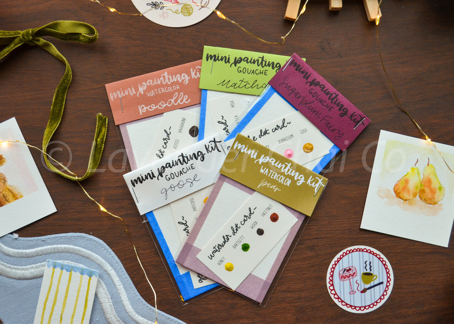 Collection of mini painting kits and art supplies on a wooden surface with decorative elements.